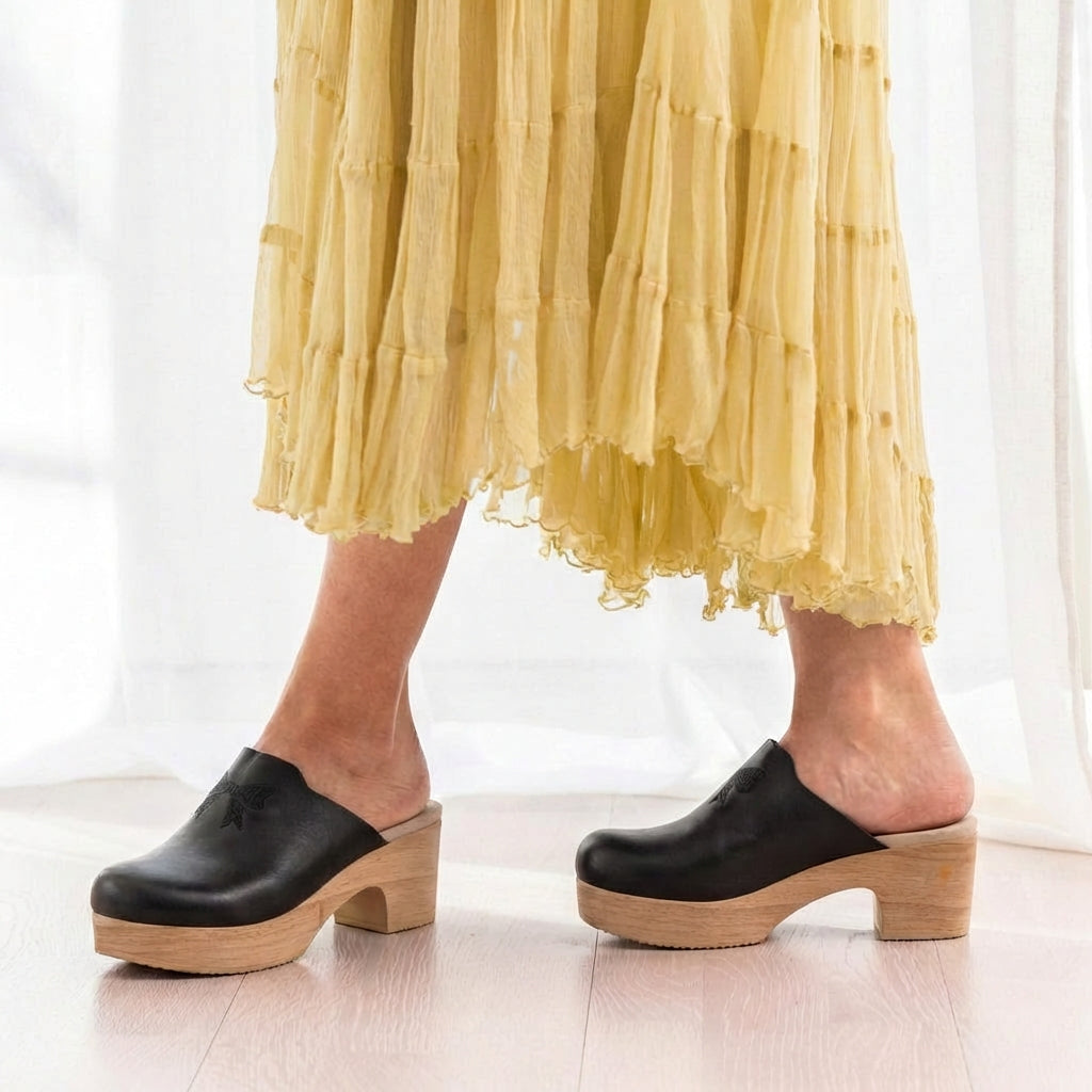 Calou Dolly Black leather clogs on flexible soles worn with a yellow skirt 
