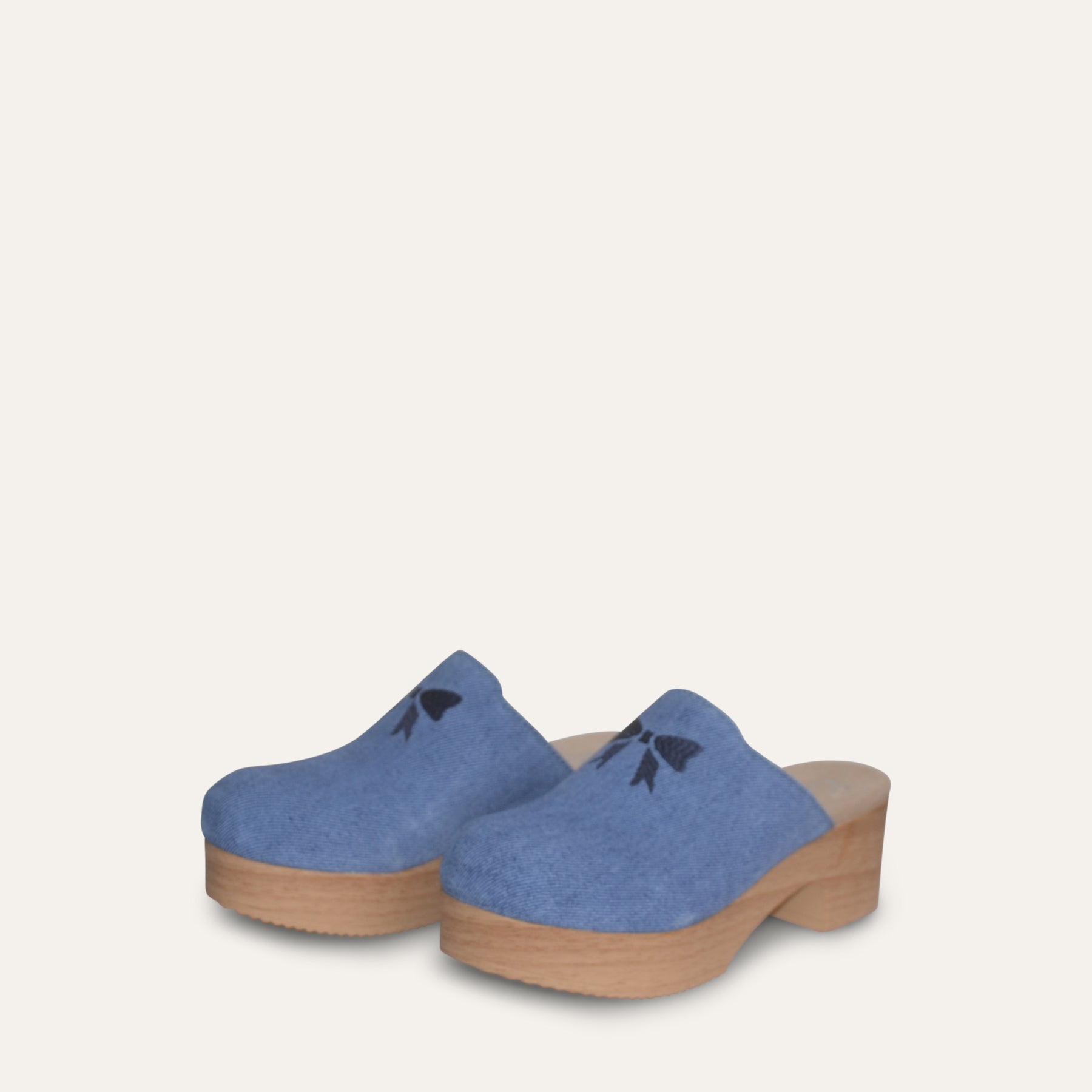 Pair of blue clogs with wooden soles on a light gray background