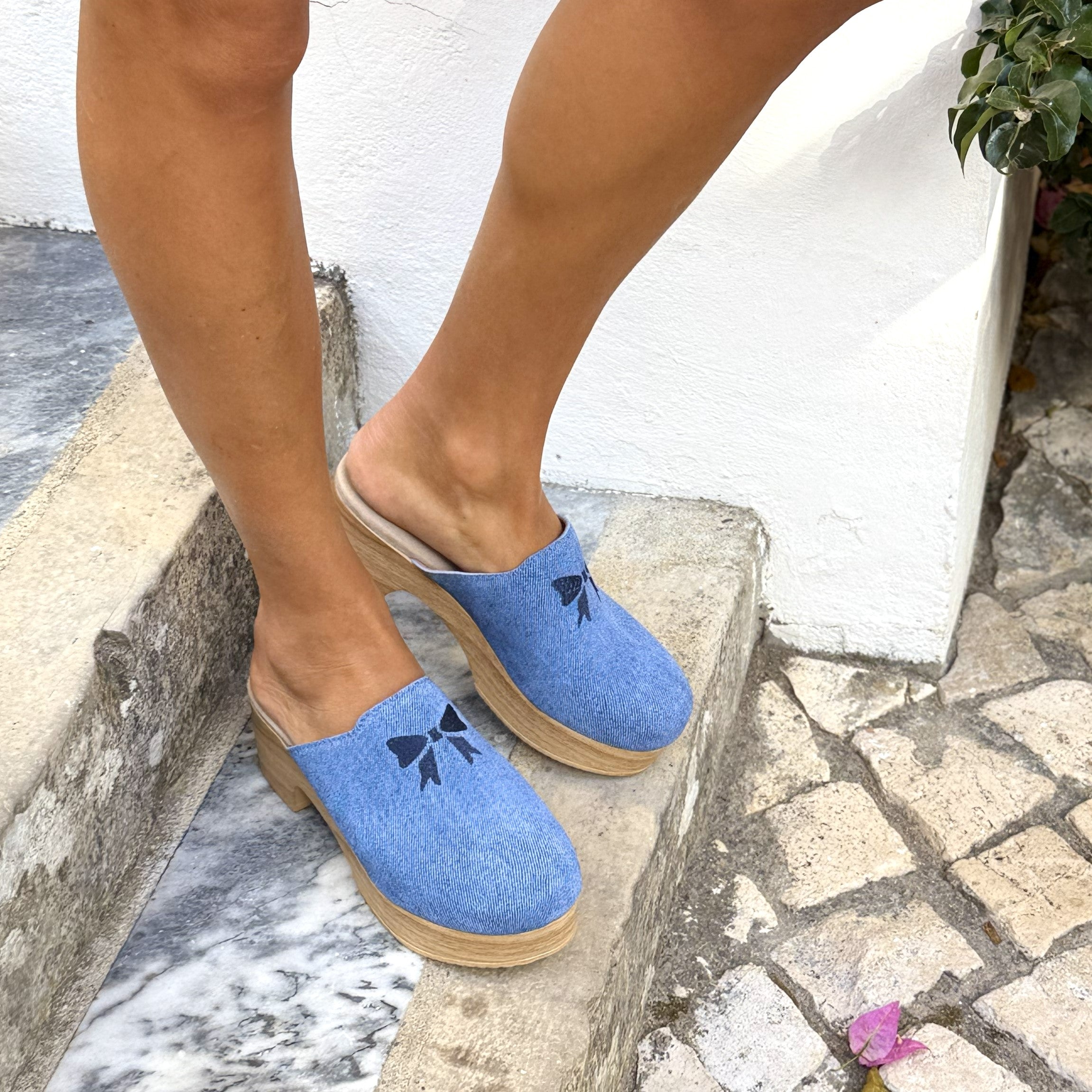 Blue flexible sole clogs with bow design worn on model