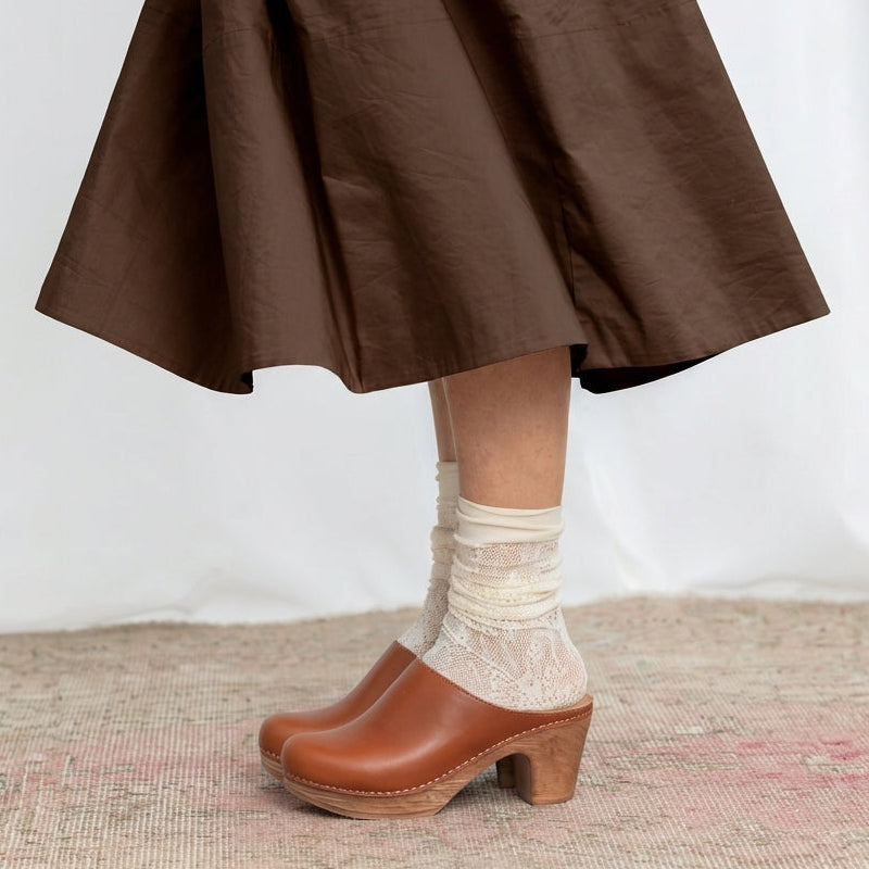 Brown skirt, white socks, and brown clogs on a neutral background